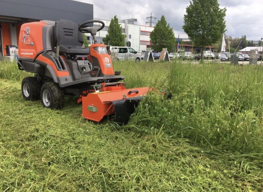 Aufsitzmäher mit Mulchgerät auf einer Wiese an einem Gewerbegebiet