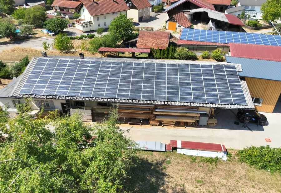 Sichtbild: Photovoltaikanlage auf einem Betriebsdach zwischen Wohnhäusern