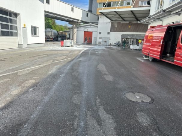 Blick auf einen gepflasterten Bereich hinter einem Gebäude mit einem roten Fahrzeug.
